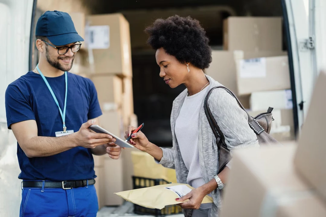 young-courier-giving-touchpad-female-customer-sign-delivery-focus-is-african-american-woman_637285-1264